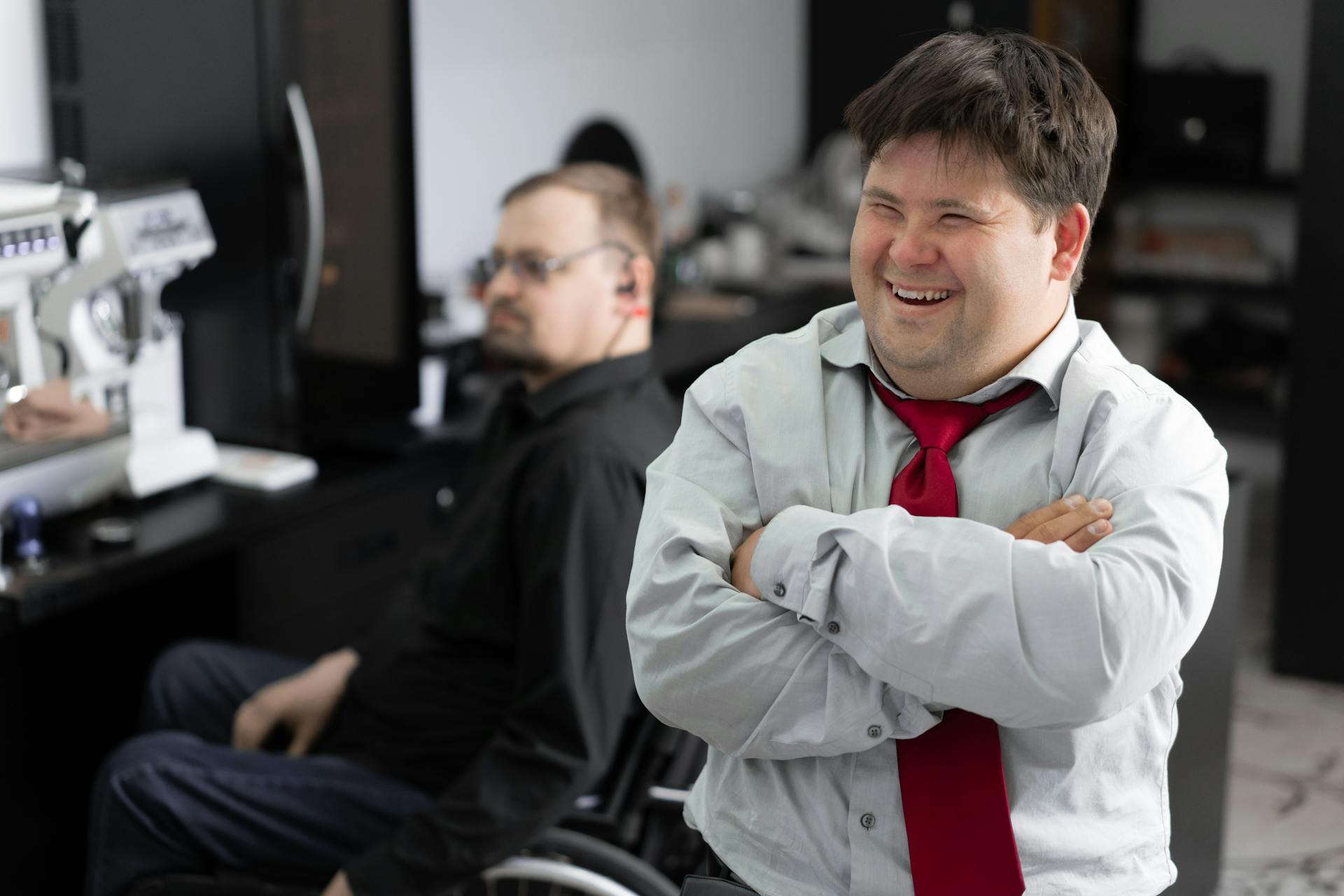 A worker with a disability laughs at a joke in the office.