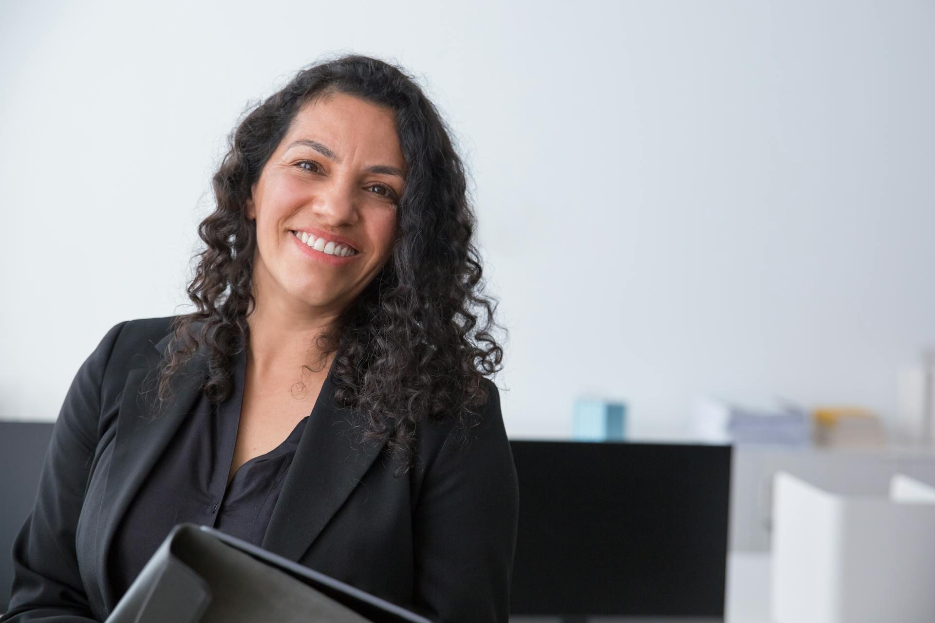 A woman smiles at the camera from behind a desk